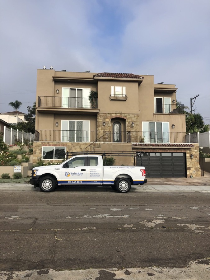Two-story stucco home repainted, PaintRite truck parked in front